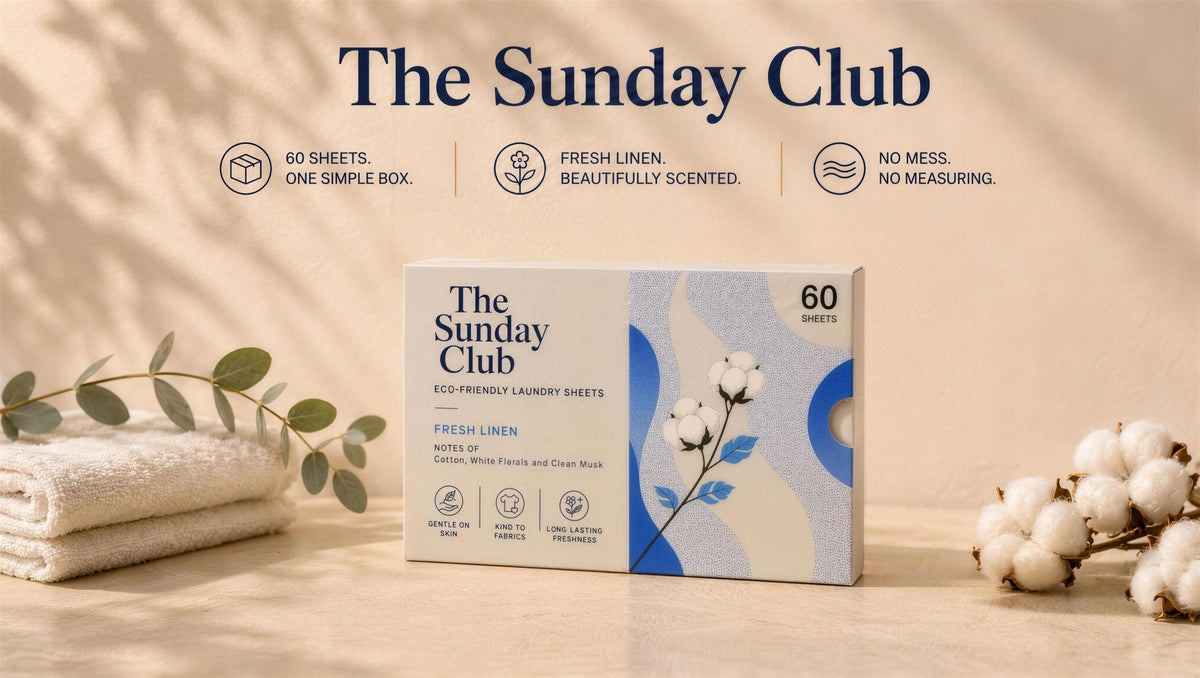 The Sunday Club eco-friendly Fresh Linen laundry detergent sheets, 60-sheet box on a warm wood surface with folded towels, eucalyptus and cotton